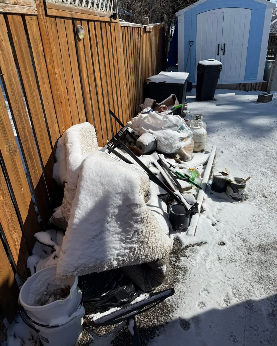 Side yard piled with old furniture and debris before junk removal
